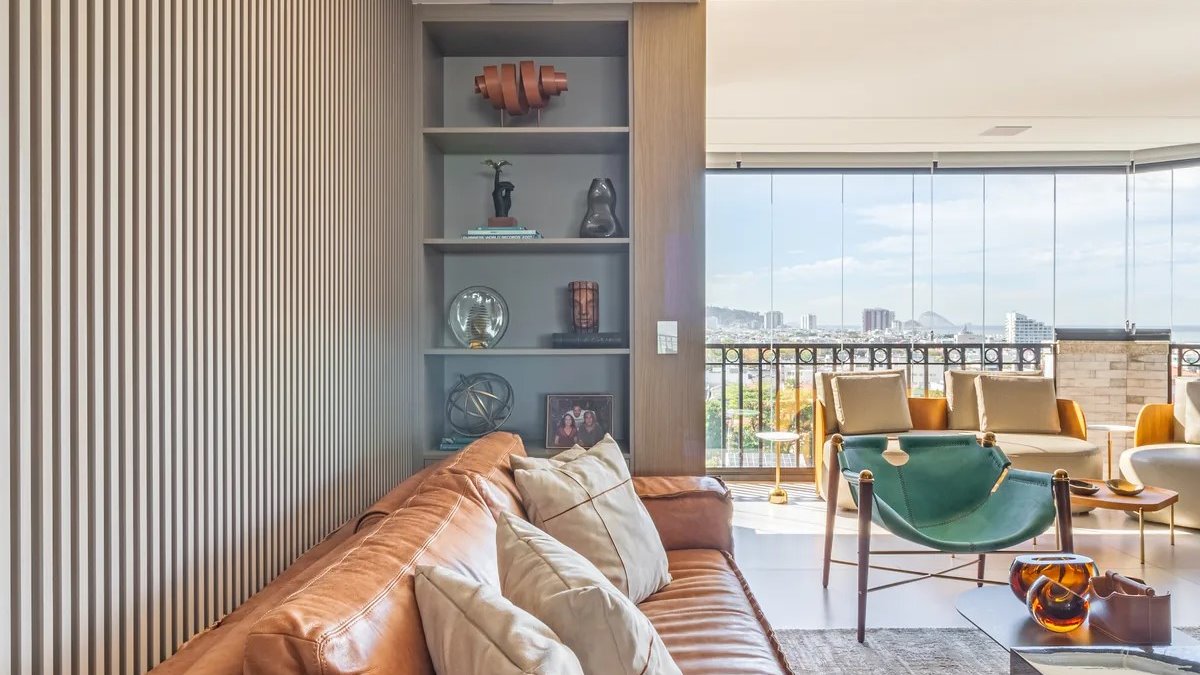 Living de apartamento de alto padrão reformado no Rio de Janeiro, com marcenaria ripada e vista para a cidade