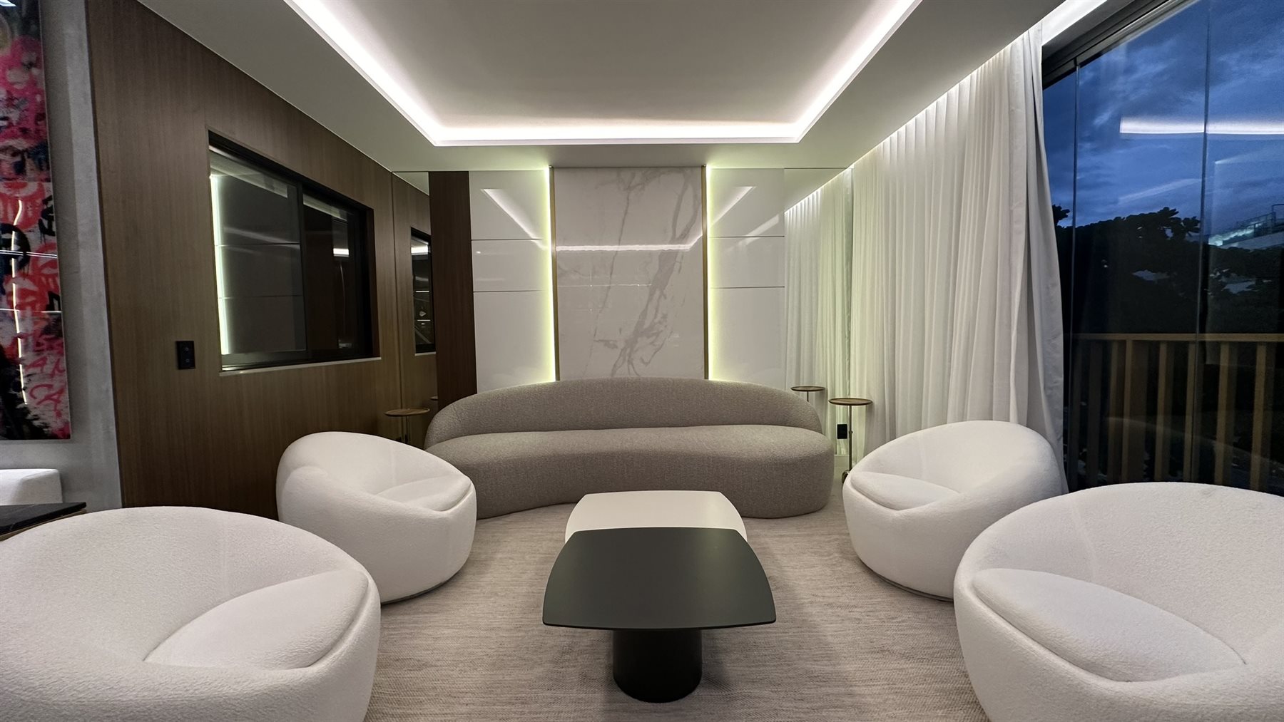 Sala de estar de alto padrão à noite com iluminação em camadas, sanca de LED e mármore iluminado, no Rio de Janeiro